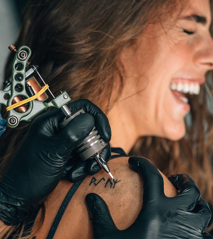 "Smiling woman getting a shoulder tattoo by a professional artist using a tattoo machine at a top notch tattoo studio."